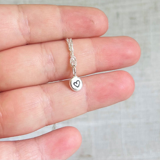 Beautiful little recycled silver nugget necklace held in hand, the little nugget is about one third or the width of a finger. 